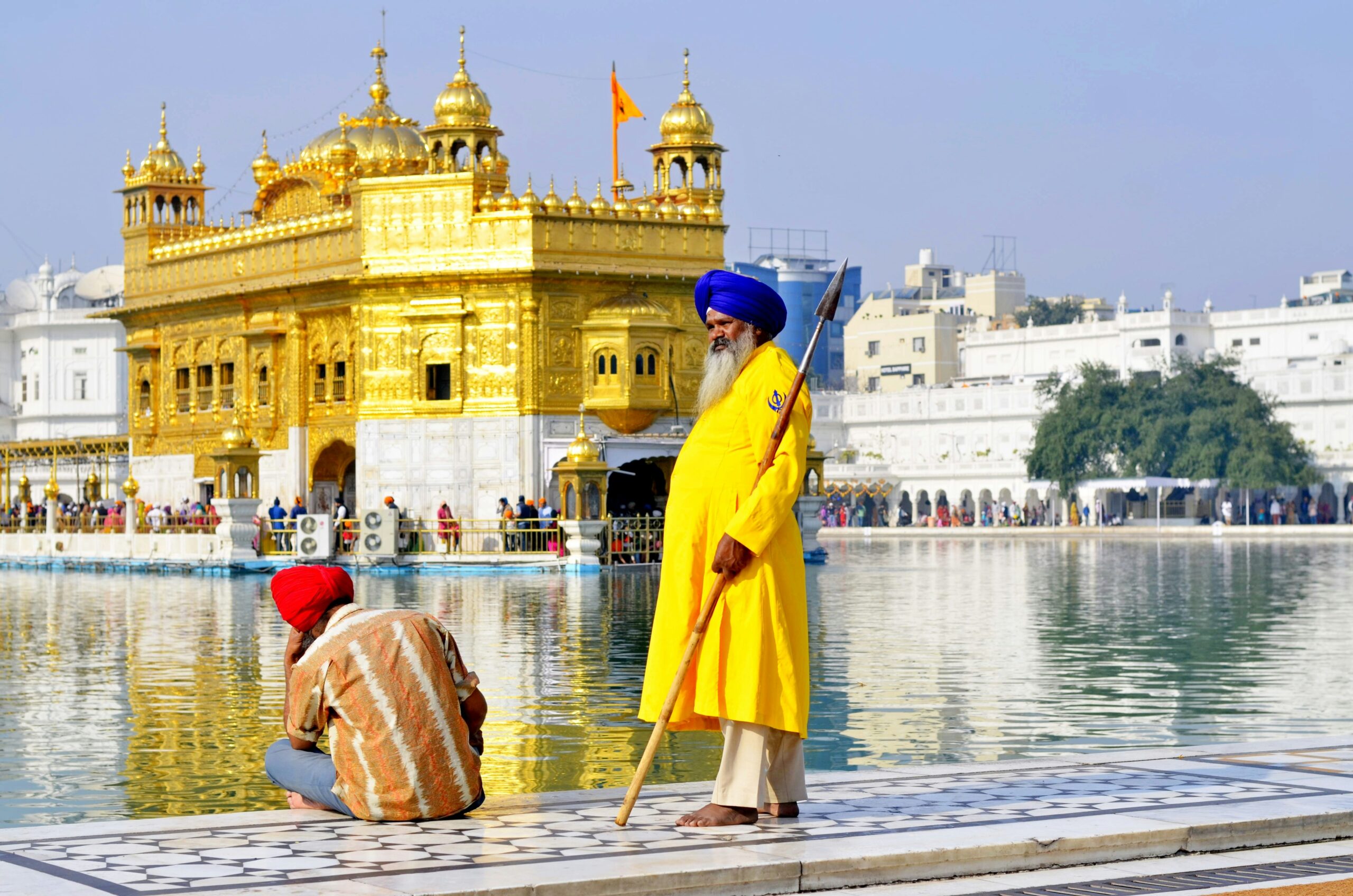 sikhism,woman in yellow coat standing on brown wooden dock during daytime