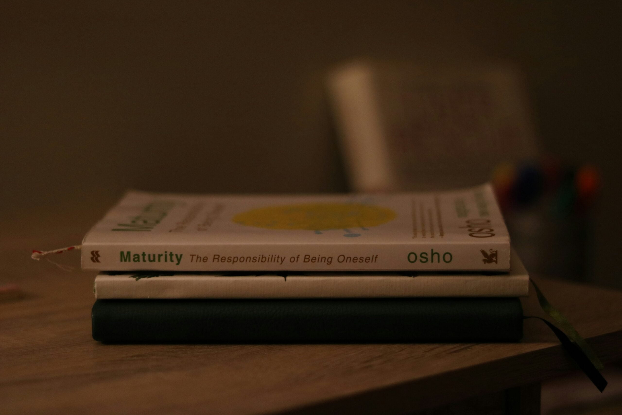 Osho's philosophy, a stack of books sitting on top of a wooden table